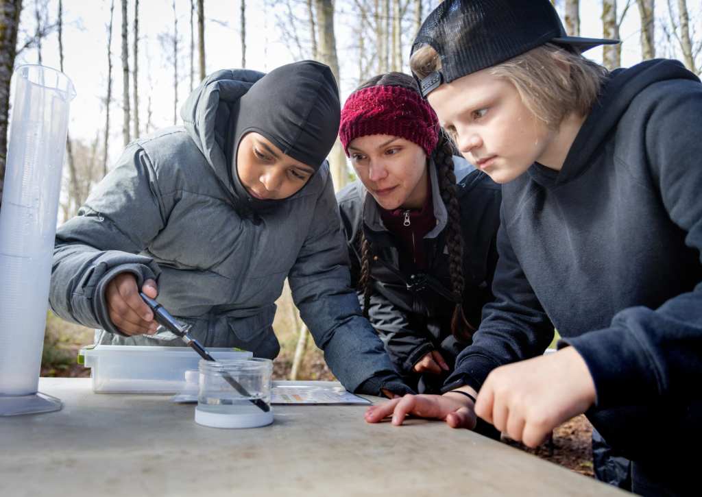 8/19 Pierce Conservation District staff help students measure the temperature of a creek water sample.