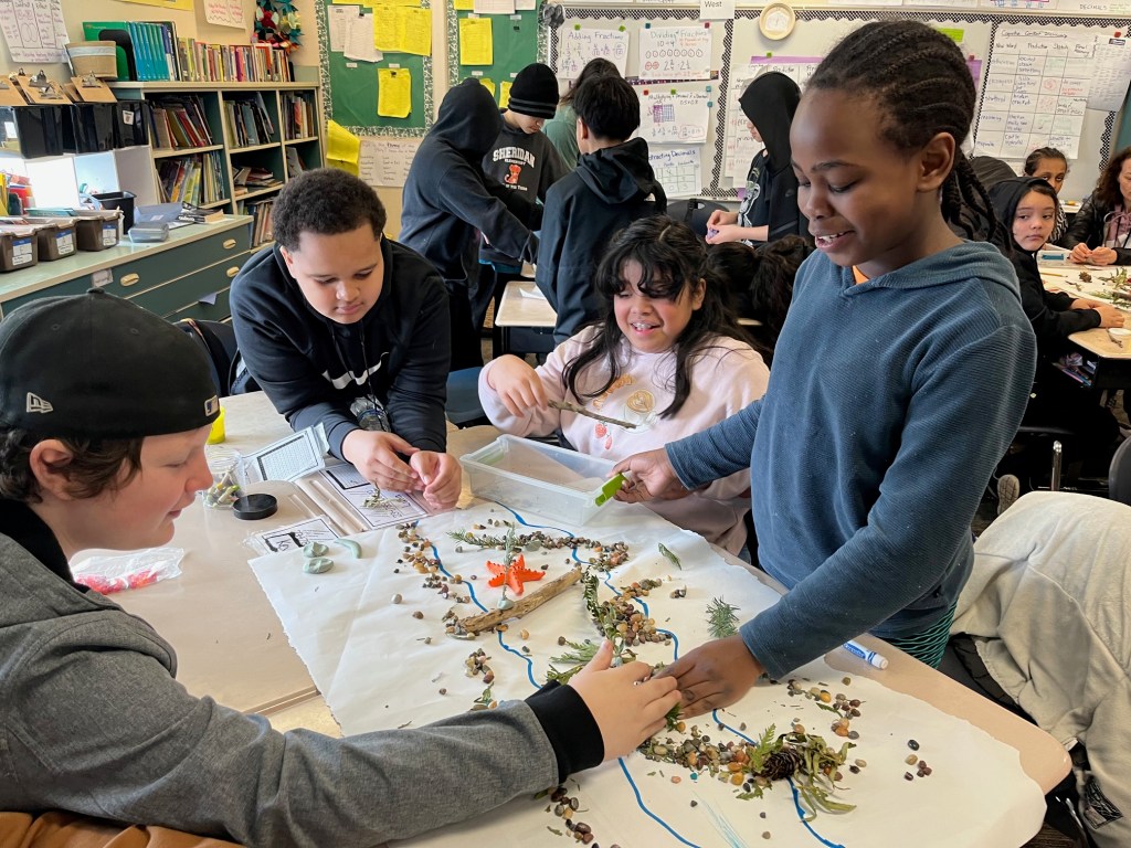Elementary students work on a model of salmon habitat